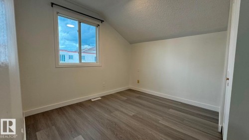 Wood-finish flooring with white baseboards, a window with a dark curtain rod, and light-colored walls - 41 Lancaster Terrace Nw, Edmonton, AB - Indoor Photo Showing Other Room
