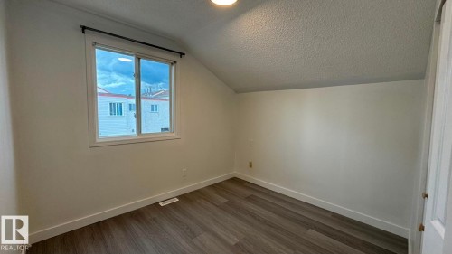 Sloped ceiling room featuring wood-finish flooring, white walls, and a recessed window - 41 Lancaster Terrace Nw, Edmonton, AB - Indoor Photo Showing Other Room