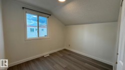 Sloped ceiling room featuring wood-finish flooring, white walls, and a recessed window - 