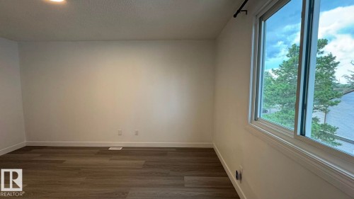 Wood-finish flooring, white painted walls, and a large window with white trim - 41 Lancaster Terrace Nw, Edmonton, AB - Indoor Photo Showing Other Room