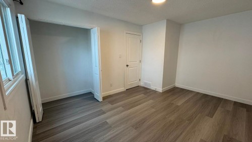 Wood-finish flooring, white walls, built-in closet, and a white interior door - 41 Lancaster Terrace Nw, Edmonton, AB - Indoor Photo Showing Other Room