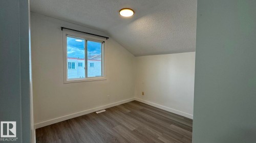 Recessed window with dark rod, wood-finish flooring, white walls, and a ceiling-mounted light fixture - 41 Lancaster Terrace Nw, Edmonton, AB - Indoor Photo Showing Other Room