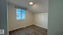Recessed window with dark rod, wood-finish flooring, white walls, and a ceiling-mounted light fixture - 