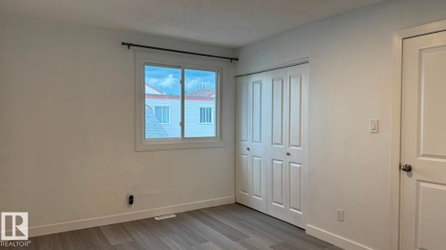Light-toned wood-finish flooring, white walls, and a window with white trim - 41 Lancaster Terrace Nw, Edmonton, AB - Indoor Photo Showing Other Room