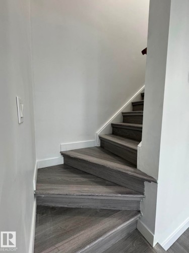Staircase featuring wood-finish treads and risers, white wall paint, and white trim - 41 Lancaster Terrace Nw, Edmonton, AB - Indoor Photo Showing Other Room