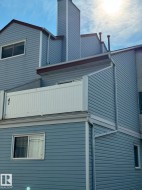 Siding exterior featuring a prominent chimney structure, multiple windows, and a white balcony railing - 