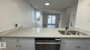 Light-toned solid surface countertop with an integrated double basin sink and gooseneck faucet, stainless steel dishwasher, and white cabinetry with brushed nickel hardware - 41 Lancaster Terrace Nw, Edmonton, AB  - Indoor Photo Showing Kitchen With Double Sink 
