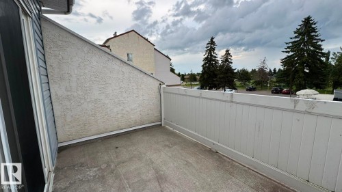 Private balcony with solid surface flooring, featuring a white privacy fence and textured stucco exterior wall - 41 Lancaster Terrace Nw, Edmonton, AB - Outdoor