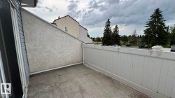 Private balcony with solid surface flooring, featuring a white privacy fence and textured stucco exterior wall - 