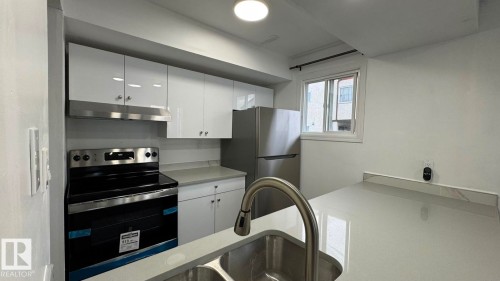Stainless steel appliances, white cabinetry, integrated sink, and light-toned countertops - 41 Lancaster Terrace Nw, Edmonton, AB - Indoor Photo Showing Kitchen
