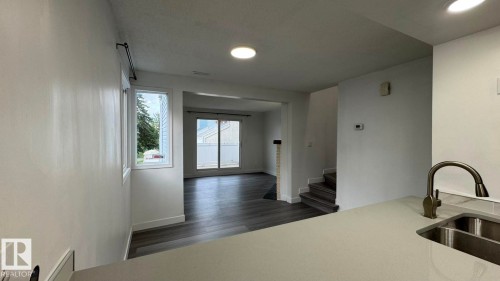 Spacious interior with wood-finish flooring, recessed lighting, and a kitchen featuring a dual-basin sink with a gooseneck faucet - 41 Lancaster Terrace Nw, Edmonton, AB - Indoor