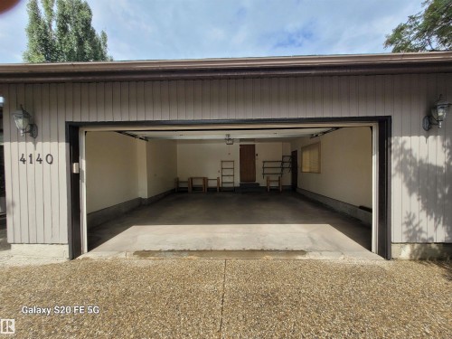 Two-car garage with vertical siding, concrete flooring, and exterior wall sconces - 4140 147 Street Nw, Edmonton, AB - Outdoor With Exterior