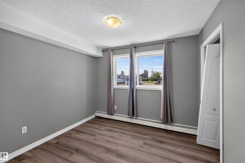 Wood-finish flooring, dual windows, ceiling-mounted light fixture, and white bi-fold closet door - #4 4616 47 St, Leduc, AB - Indoor Photo Showing Other Room