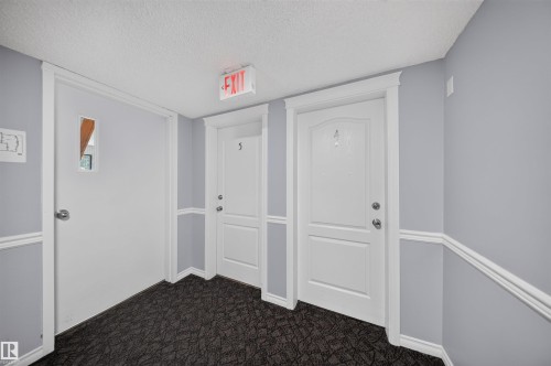 Gray walls with white trim, dark patterned carpeting, and white paneled doors - #4 4616 47 St, Leduc, AB - Indoor Photo Showing Other Room