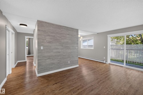 Wood-finish flooring throughout, light gray wall finishes, and a gray accent wall - #4 4616 47 St, Leduc, AB - Indoor Photo Showing Other Room