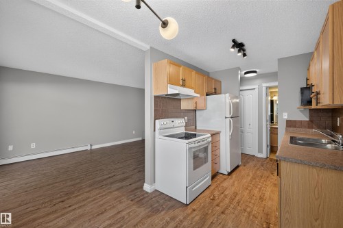Open-concept layout featuring wood-finish flooring, oak cabinetry, and a tile backsplash - #4 4616 47 St, Leduc, AB - Indoor Photo Showing Kitchen With Double Sink