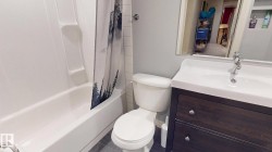 Full bathroom featuring a wood-finish vanity with dual drawers, white porcelain sink, and chrome faucet - 