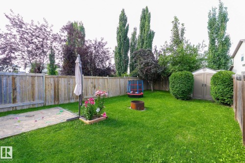 Expansive fenced backyard featuring a grassy lawn, sand area, and storage shed - 107 Hartwick Loop, Spruce Grove, AB - Outdoor With Backyard