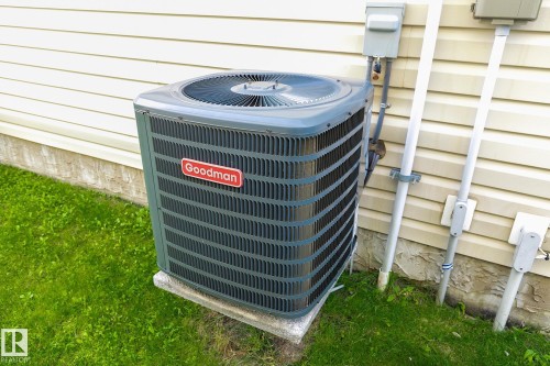 Goodman HVAC unit on a concrete pad, set against light-colored horizontal siding - 107 Hartwick Loop, Spruce Grove, AB - Outdoor