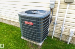 Goodman HVAC unit on a concrete pad, set against light-colored horizontal siding - 