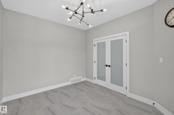 Room featuring a contemporary chandelier, light gray walls, and gray-toned tile flooring - 