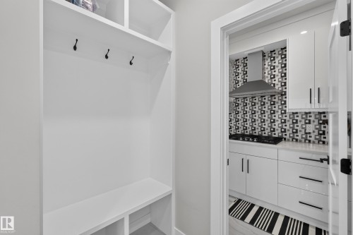Built-in white mudroom storage with black coat hooks and lower cubbies - 4703 41 Street, Beaumont, AB - Indoor