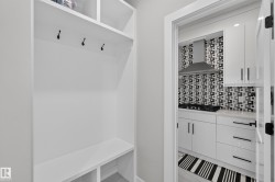 Built-in white mudroom storage with black coat hooks and lower cubbies - 