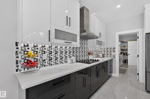 Contemporary kitchen featuring high-gloss cabinetry, a mosaic tile backsplash, a built-in cooktop, and a stainless steel range hood - 4703 41 Street, Beaumont, AB - Indoor Photo Showing Kitchen With Upgraded Kitchen
