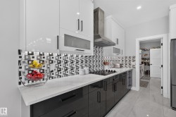 Contemporary kitchen featuring high-gloss cabinetry, a mosaic tile backsplash, a built-in cooktop, and a stainless steel range hood - 