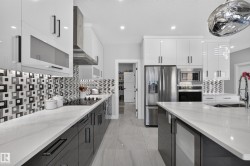Modern kitchen featuring a large central island with a sink, white quartz countertops, and sleek white and dark gray cabinetry - 