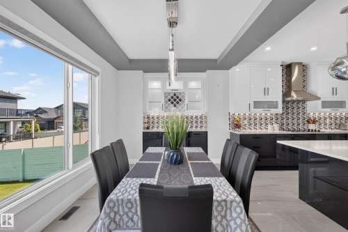 Spacious dining area featuring a large picture window, tray ceiling detail, and contemporary lighting fixture - 4703 41 Street, Beaumont, AB - Indoor Photo Showing Dining Room