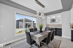 Dining area featuring a built-in wet bar with white upper cabinetry, dark lower cabinetry, and a wine rack - 