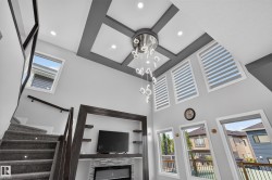 Vaulted living area featuring a decorative tray ceiling with recessed lighting and a contemporary chandelier - 