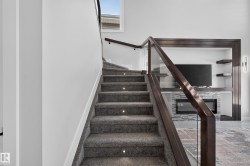 Carpeted staircase with integrated step lighting and dark wood-finish and glass railing - 