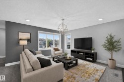 Spacious living area featuring a large window, recessed lighting, a modern chandelier, and a neutral color palette - 