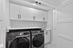 Dedicated laundry space featuring a utility sink, white cabinetry with matte black hardware, and an expansive countertop - 