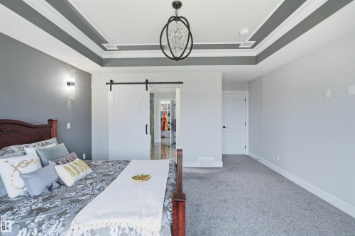 Tray ceiling with accent paint, illuminated by a decorative chandelier - 4703 41 Street, Beaumont, AB - Indoor Photo Showing Bedroom