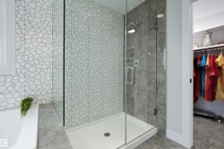 Walk-in shower featuring a glass enclosure and textured pebble-style tiling - 