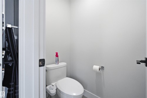Compact water closet with a contemporary toilet, light gray walls, and dark bronze door hardware - 4703 41 Street, Beaumont, AB - Indoor Photo Showing Bathroom