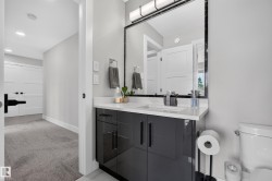Bathroom featuring a white quartz countertop, undermount sink, and a dark high-gloss vanity with modern hardware - 