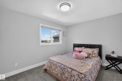 Carpeted bedroom featuring light gray walls, a flush-mount ceiling light fixture, a white-framed window, and white baseboards - 