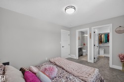 Neutral-toned bedroom featuring plush gray carpeting and a modern flush-mount ceiling light - 