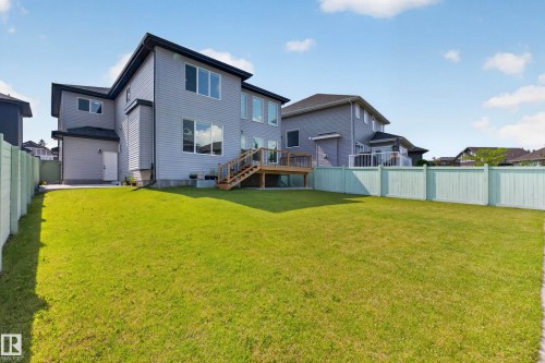Spacious backyard featuring a large lawn area and light green privacy fencing - 4703 41 Street, Beaumont, AB - Outdoor With Backyard With Exterior
