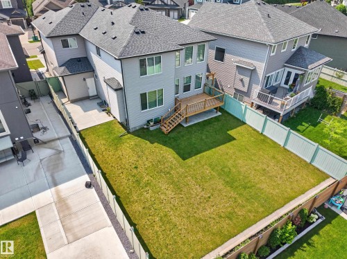 Expansive backyard featuring a manicured lawn, a two-level wood deck, a concrete patio, and a light-colored privacy fence - 4703 41 Street, Beaumont, AB - Outdoor