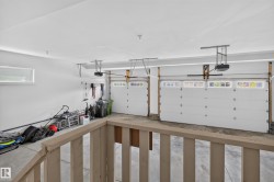 Two-car garage featuring white paneled doors with upper window inserts, automatic openers, a horizontal window, and concrete flooring - 