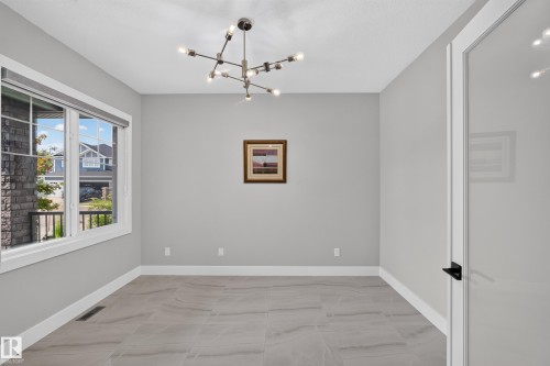 Contemporary chandelier illuminating a room with large format tile flooring, light gray walls, and white baseboards - 4703 41 Street, Beaumont, AB - Indoor Photo Showing Other Room