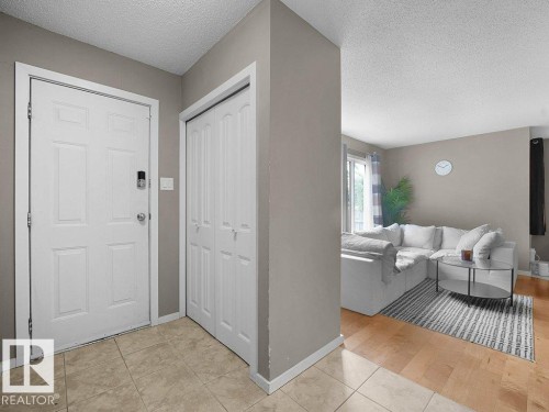 Entryway with tiled flooring and bi-fold closet doors, transitioning to wood-finish flooring in the living area - 34 Amberly Court Nw, Edmonton, AB - Indoor Photo Showing Other Room
