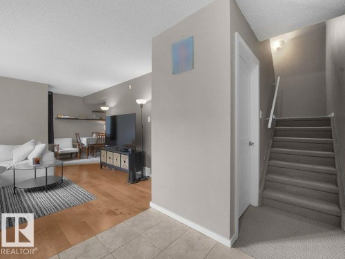 Tiled entry flooring, wood-finish flooring, carpeted staircase with white railing, neutral wall paint, and recessed ceiling lighting - 34 Amberly Court Nw, Edmonton, AB - Indoor Photo Showing Other Room