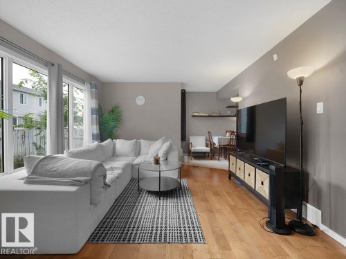Wood-finish flooring, floor-to-ceiling windows, recessed lighting, and wall-mounted shelving - 34 Amberly Court Nw, Edmonton, AB - Indoor Photo Showing Living Room