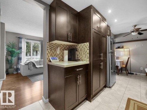Dark wood-finish cabinetry with silver-tone hardware, a mosaic tile backsplash, and a light-toned countertop - 34 Amberly Court Nw, Edmonton, AB - Indoor